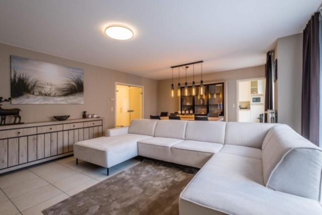 un soggiorno con divano bianco e una cucina di Appartement GT a Blankenberge