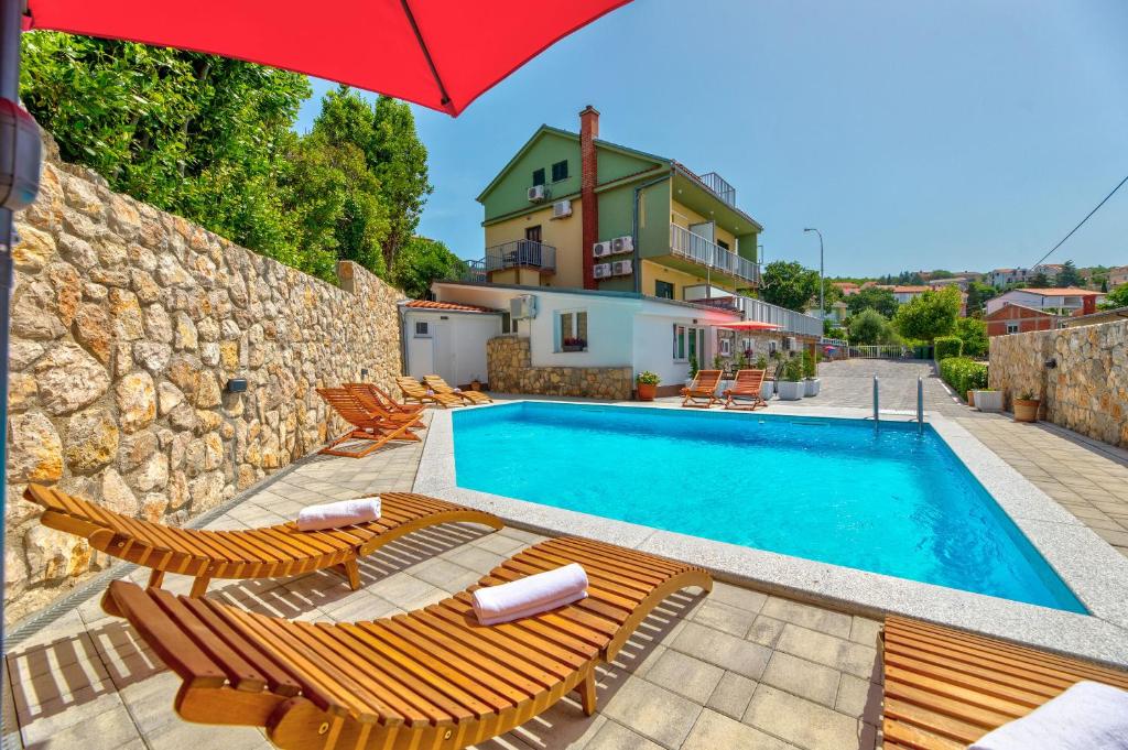 a pool with chairs and an umbrella and a house at Apartments Jasna in Crikvenica