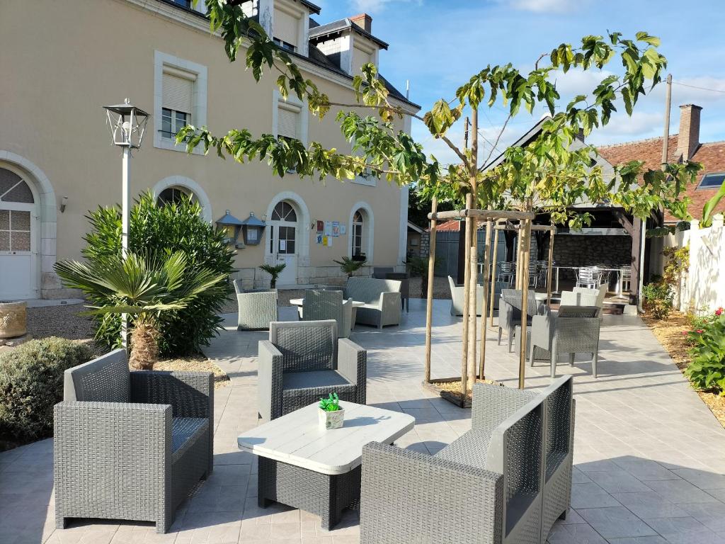 eine Terrasse mit Stühlen und Tischen vor einem Gebäude in der Unterkunft Hôtel Restaurant Le Moulin de la Renne Adults Only proche Zoo de Beauval in Thésée