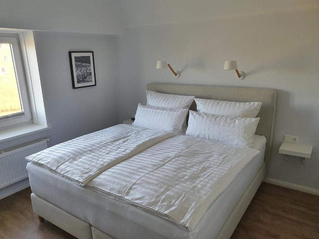 a bedroom with a large bed with white sheets and pillows at Apartment Südwesthörn in Emmelsbüll-Horsbüll