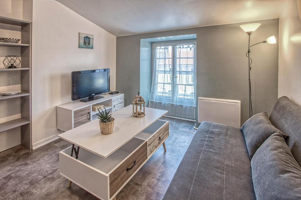 uma sala de estar com um sofá e uma televisão em Centre-ville - calme -proche gare em Angoulême
