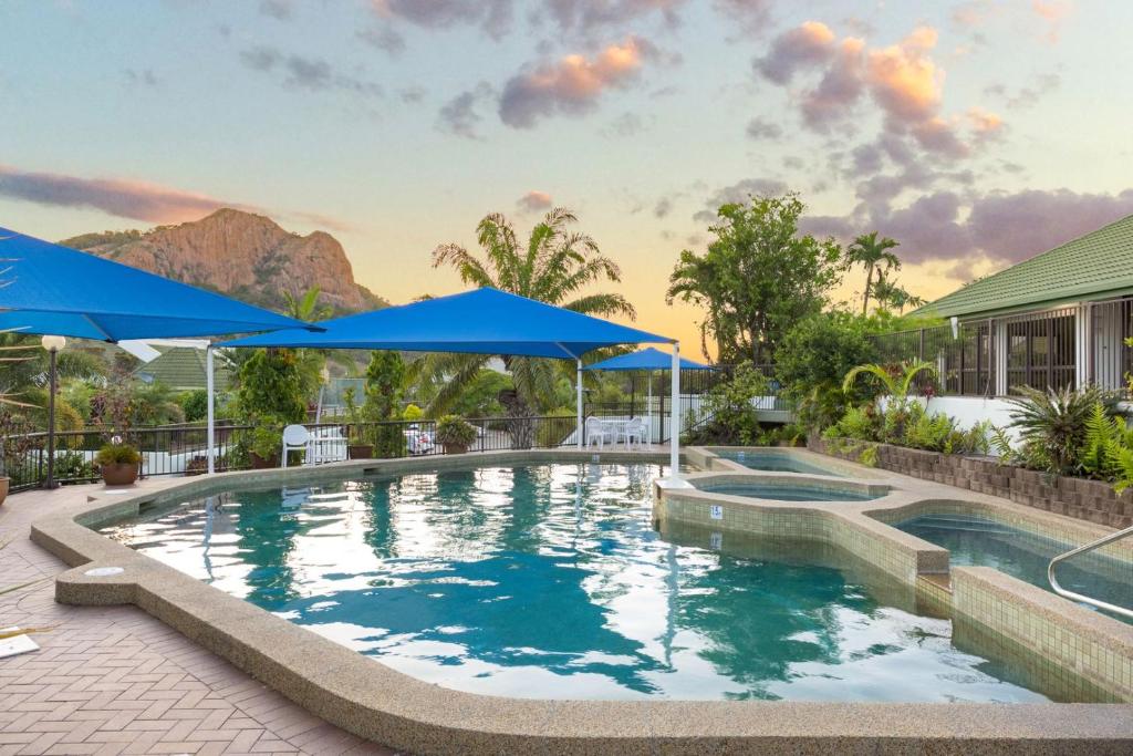 une piscine avec des parasols bleus et une maison dans l'établissement EXECUTIVE PROPERTIES IN NORTH WARD TOWNSVILLE and ON MAGNETIC ISLAND, à Townsville