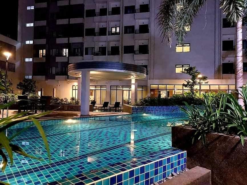a swimming pool in front of a building at night at SM Spring Residences Tower 2 Condominium Bicutan Parañaque Cozy Condo in Manila