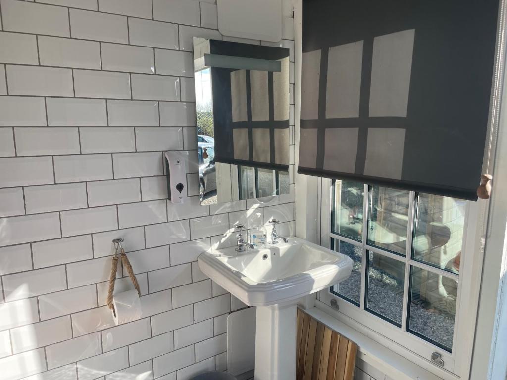 a white bathroom with a sink and a mirror at Penhallow House in Newlyn East