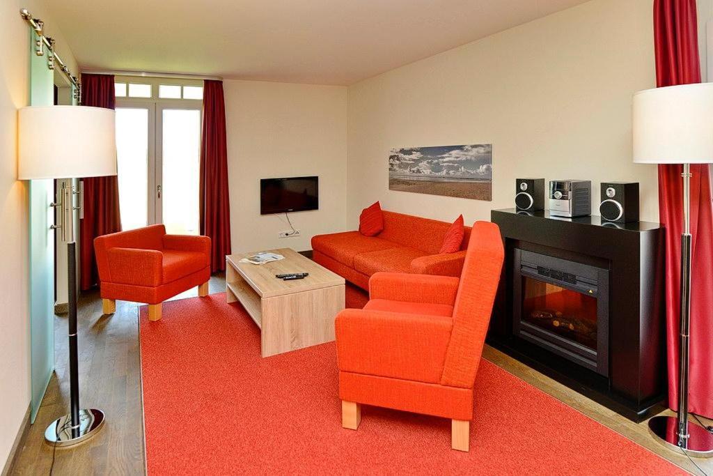 a living room with orange furniture and a fireplace at Resort Deichgraf Resort Deichgraf 31-02 in Wremen