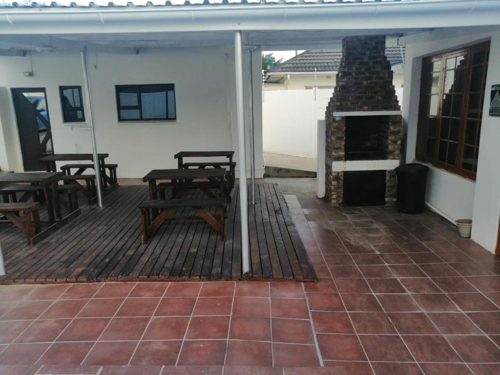 a deck with tables and a fireplace on a house at G Guest House in King Williamʼs Town