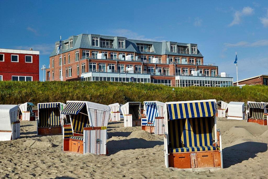 a row of beach chairs on the sand in front of a building at Aparthotel Anna Düne Aparthotel Anna Düne 1-22 in Wangerooge