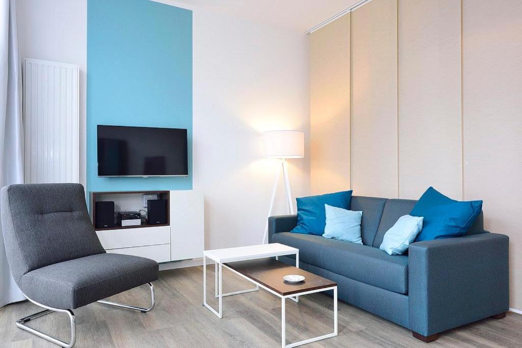 a living room with a blue couch and a chair at Aparthotel Anna Düne Aparthotel Anna Düne 0-07 in Wangerooge