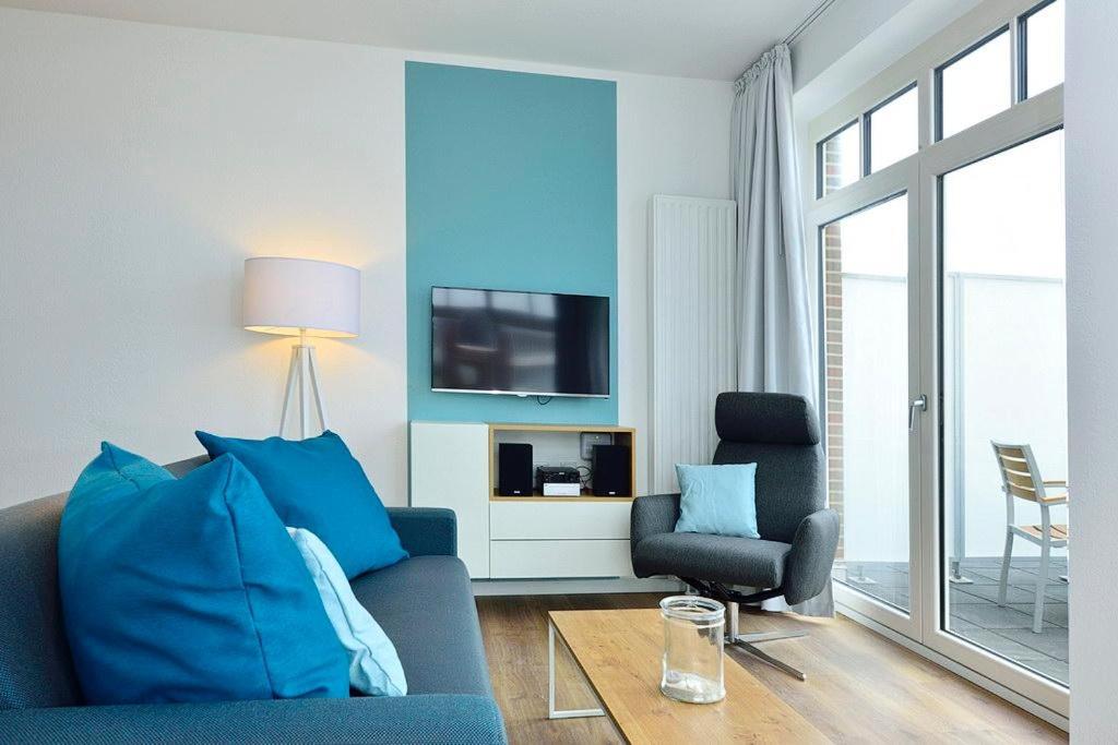 a living room with a blue couch and a tv at Aparthotel Anna Düne Aparthotel Anna Düne 2-38 in Wangerooge
