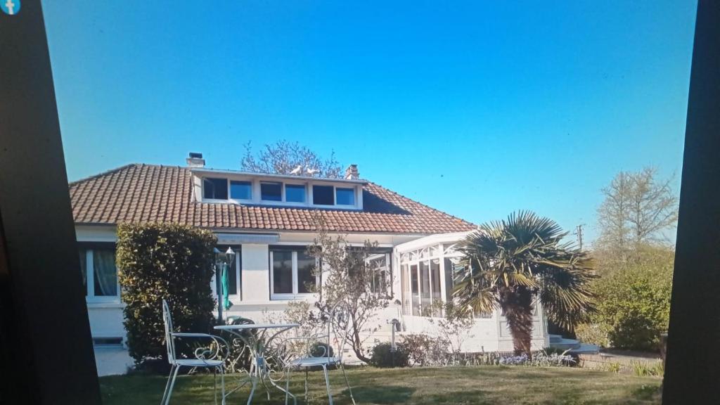 ein weißes Haus mit einer Palme im Hof in der Unterkunft Ravissante suite.chambre d hôte in Saint-Valéry-en-Caux