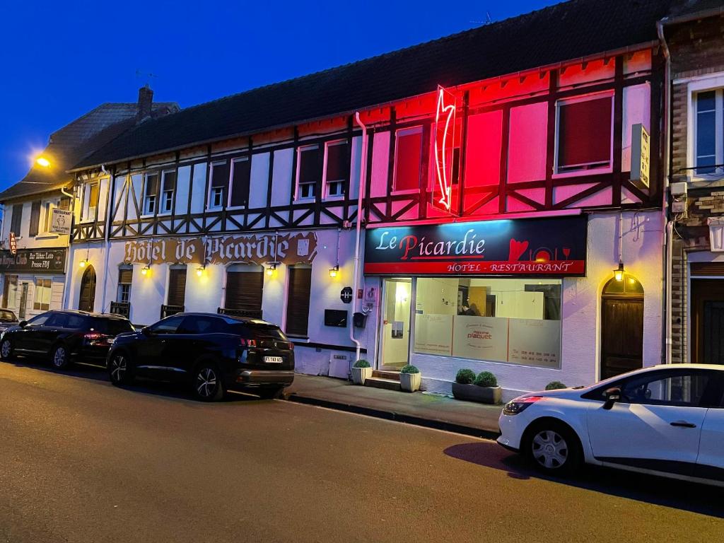 eine Straße mit Autos, die vor einem Gebäude geparkt sind in der Unterkunft HÔTEL RESTAURANT LE PICARDIE in Chauny