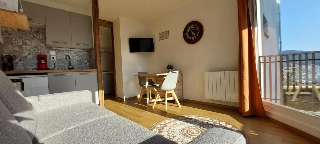 un salon avec une cuisine et une table avec une horloge dans l'établissement La Belette, à Gérardmer