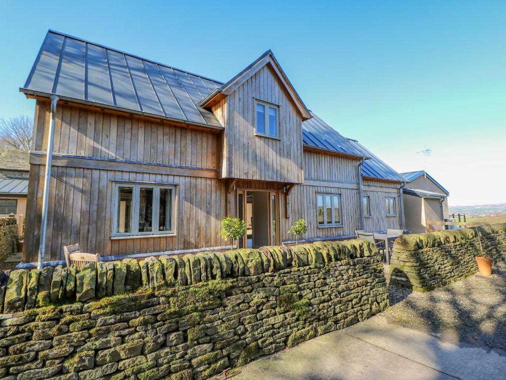 a large wooden house with a stone wall at Oak Cottage in Rochdale