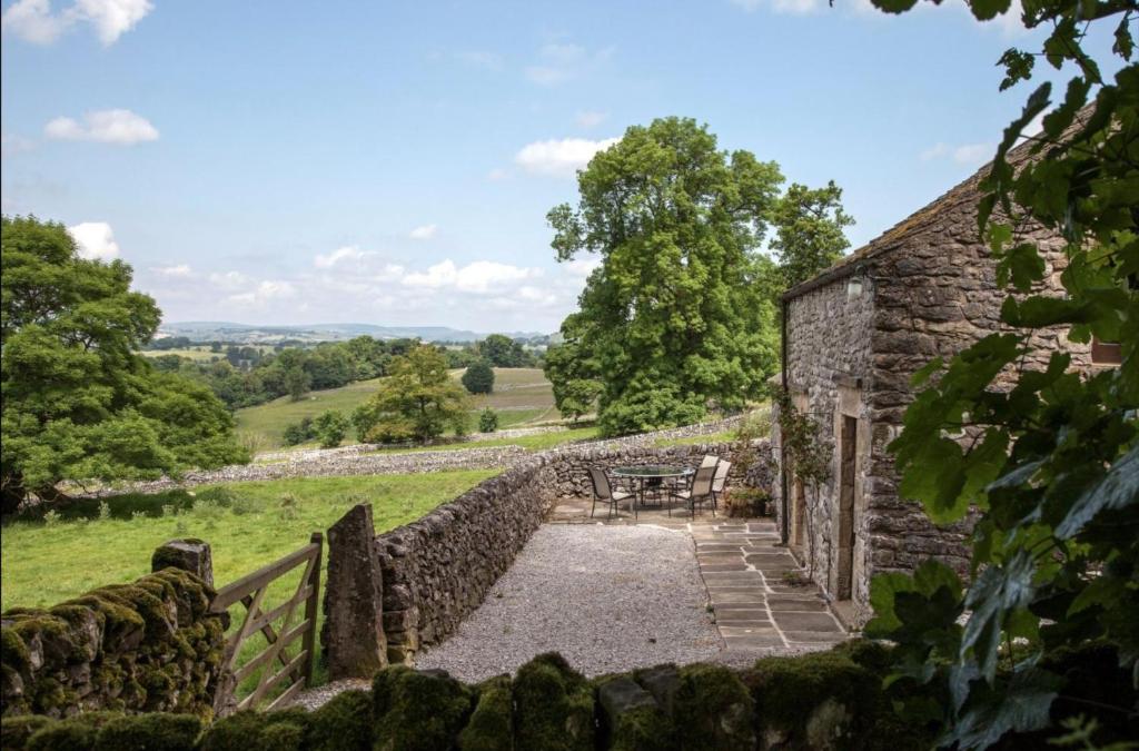 an external view of a stone house with a stone wall at Cruck Cottage in Buxton