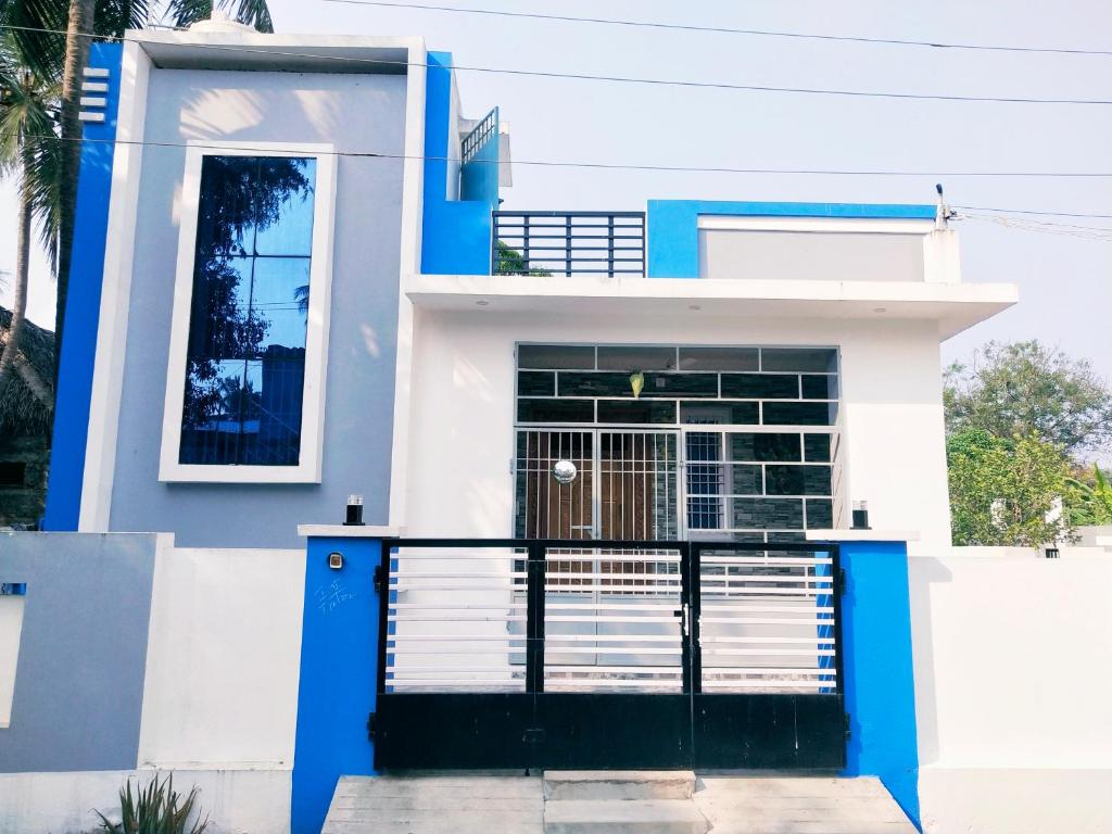 a white and blue house with a gate at Villa Blossom, Near Serenity Beach in Puducherry