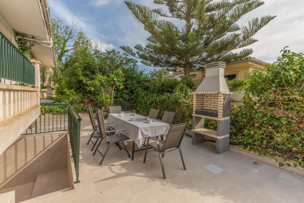 eine Terrasse mit einem Tisch, Stühlen und einem Grill in der Unterkunft Villa con jardin cerca de la playa in Muro