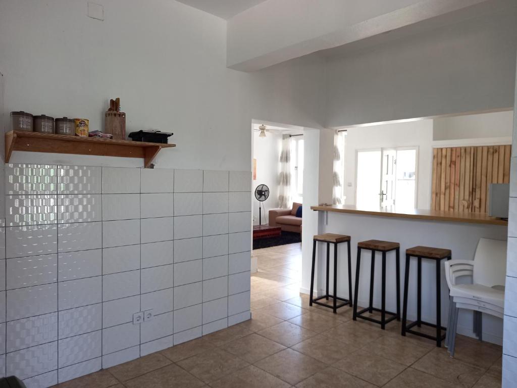 eine Küche mit weißen Fliesen und Hockern in einem Zimmer in der Unterkunft Casa Cinza in Ponta do Ouro
