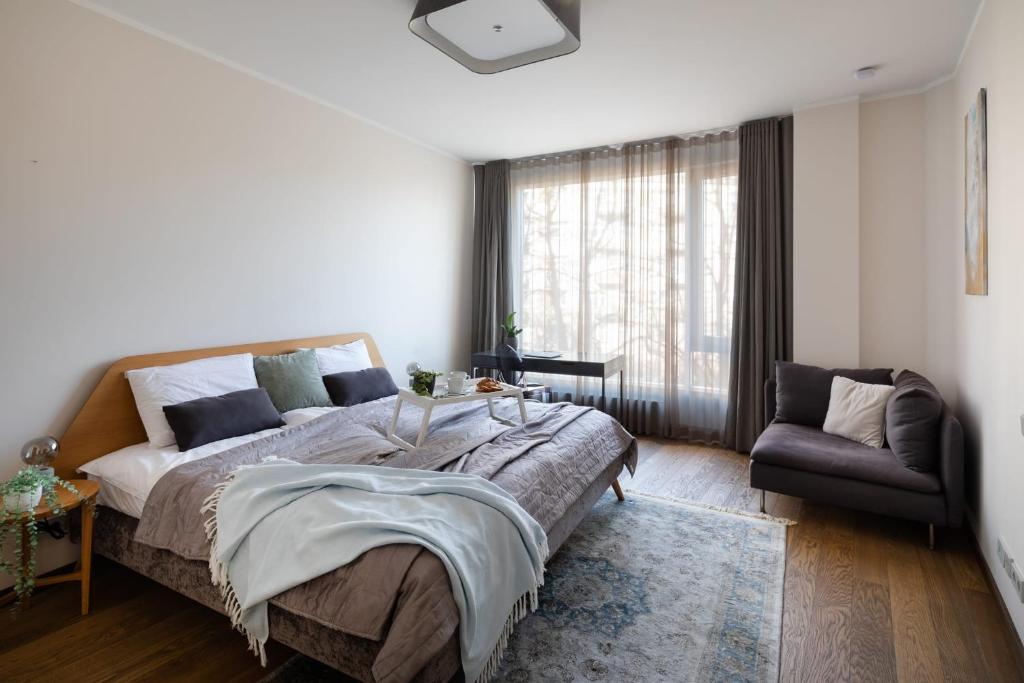 a bedroom with a bed and a chair and a window at Riga Riverside Spacious One Bedroom Apartment in Rīga