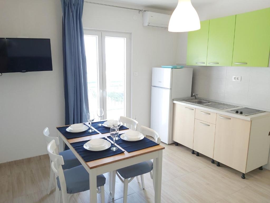 a kitchen with a table and chairs and a kitchen with a table and a table at Apartman Ariana in Gradac