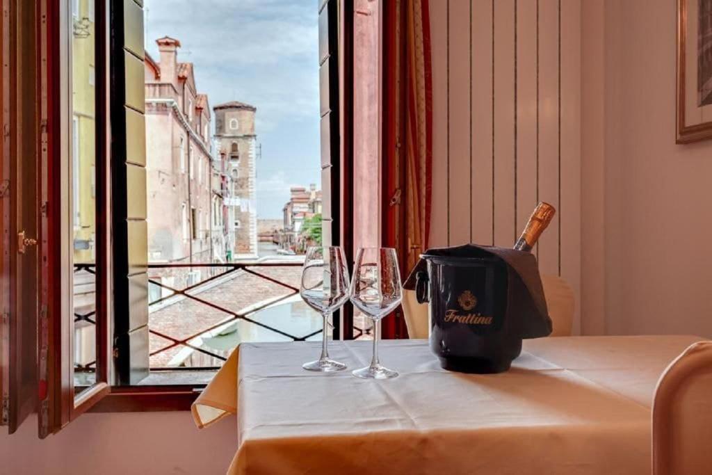 uma mesa com dois copos de vinho e um saco em Heart of Biennale em Veneza