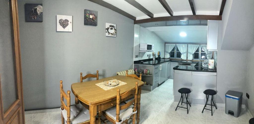 cocina y comedor con mesa de madera y sillas en El Rincón del Único en Oviñana