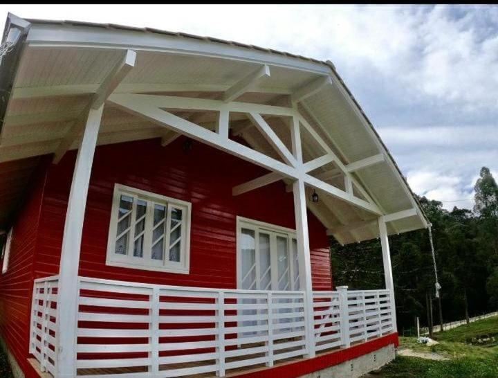 uma casa vermelha com uma cerca branca à volta. em Casa de Campo Machado em Urubici