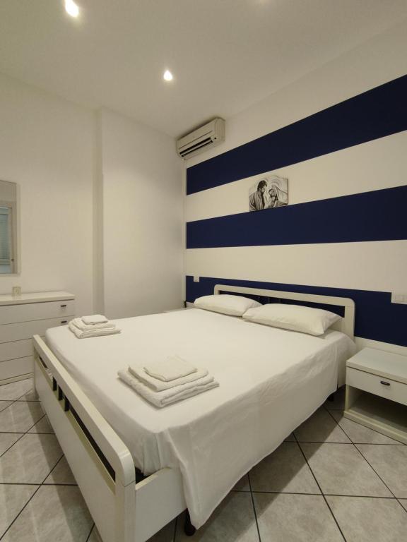 um quarto com uma cama branca com riscas azuis e brancas em Ponente em Donnalucata