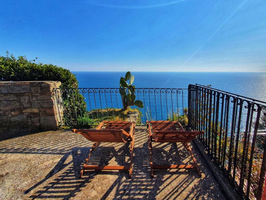 two wooden chairs sitting on a balcony overlooking the ocean at La Terrazza Sul Blu in Corniglia