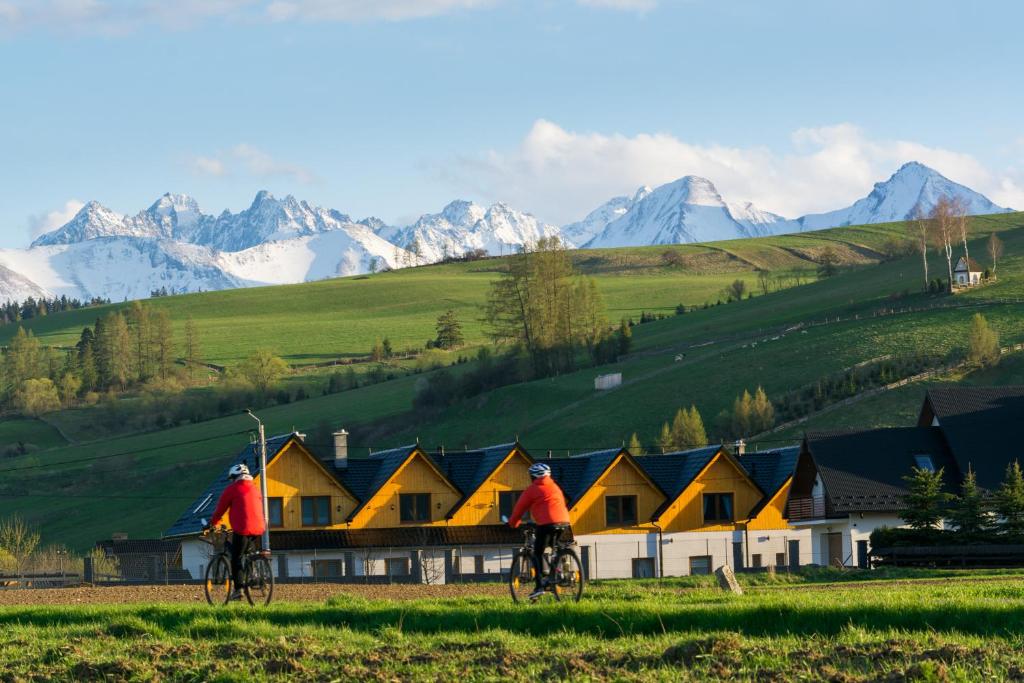 two people riding bikes in a field with mountains in the background at DW KINGA & DOMKI na Granicznej z balią w ogrodzie in Kacwin