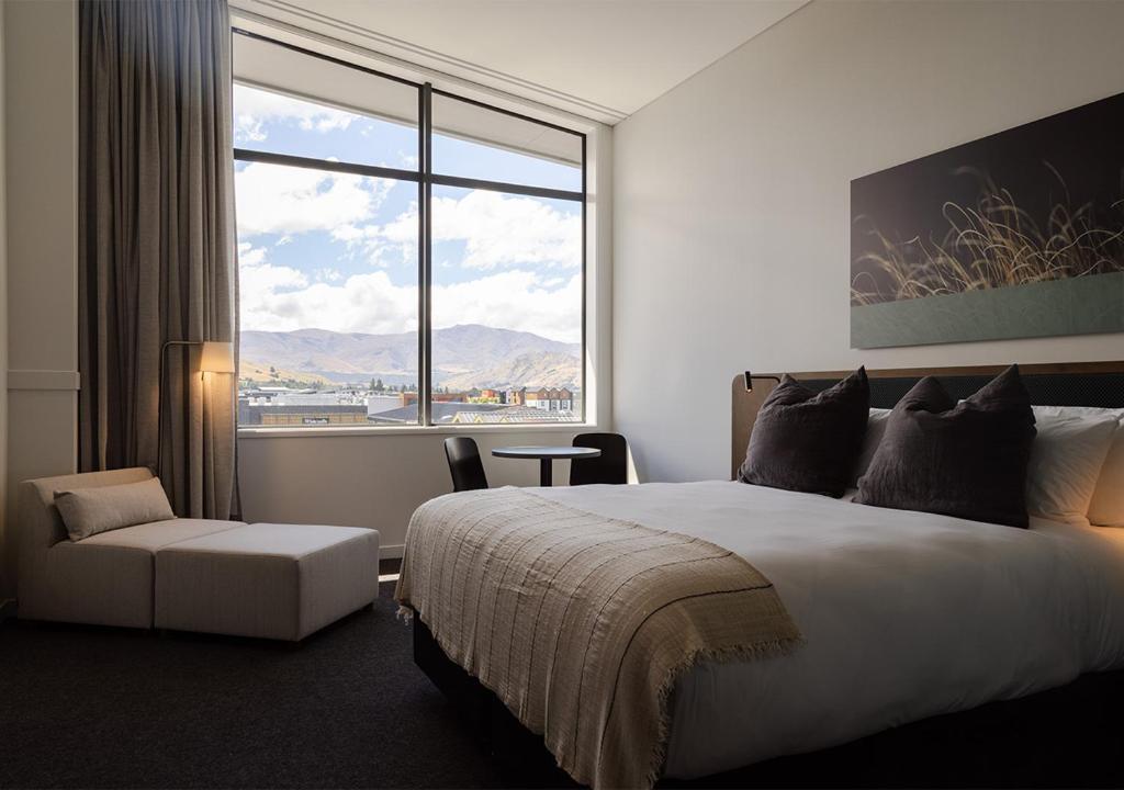 a hotel room with a bed and a large window at Sudima Queenstown Five Mile in Queenstown