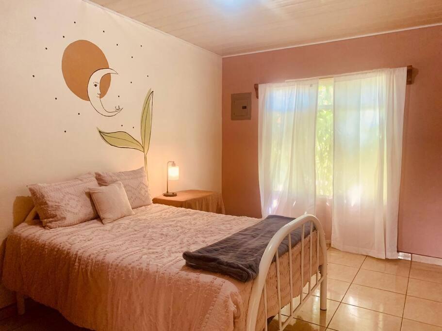 1 dormitorio con cama y ventana grande en Charming Casa Aura, near lake Arenal in Nuevo arenal, pet friendly- Casas Airelibre, en Nuevo Arenal