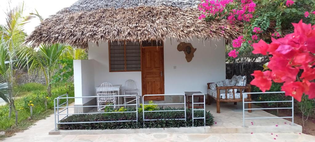a small white house with a thatch roof at PWANI HOUSE cottage in Watamu