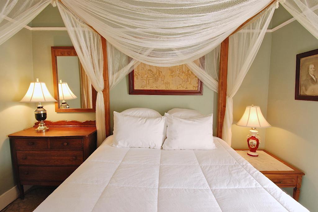 1 dormitorio con cama con dosel y almohadas blancas en Yankee Peddler Inn, en Newport