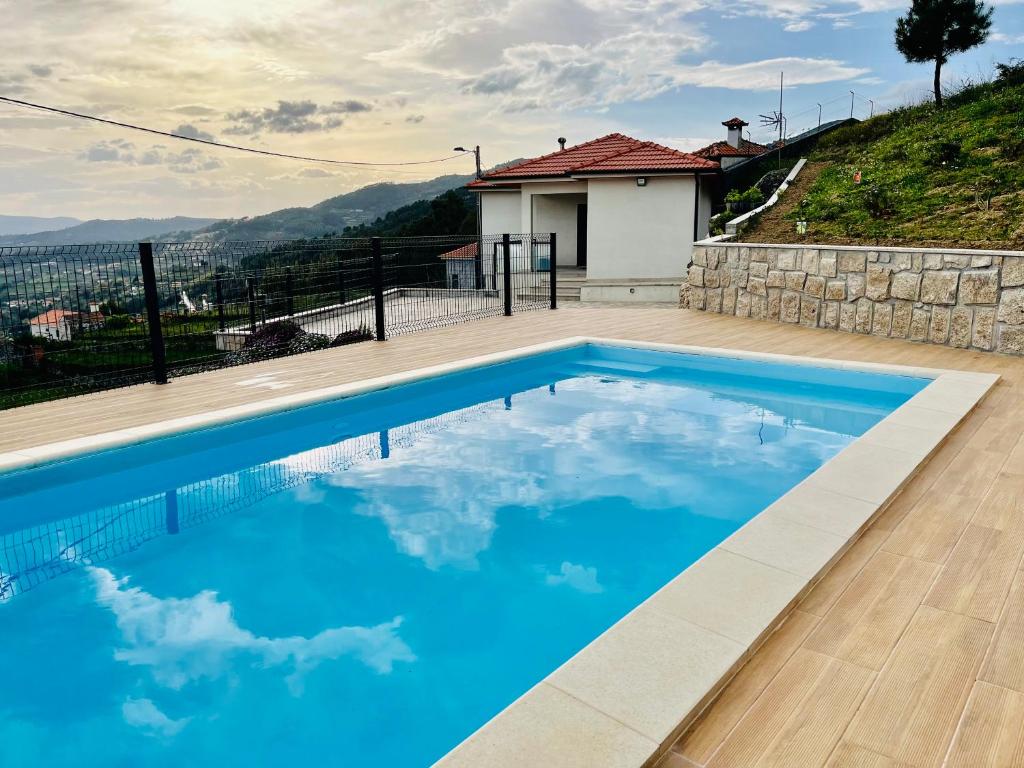 a swimming pool with blue water in front of a house at Casa da Sacota - Douro View in Baião