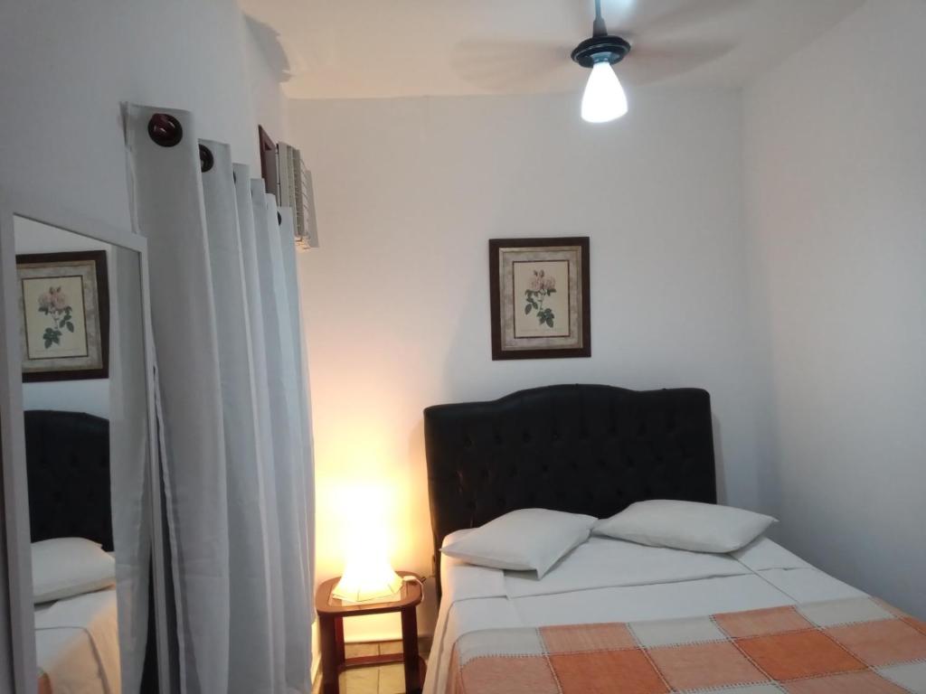 een slaapkamer met een bed en een lamp op een tafel bij Suíte Cleo in Cabo Frio