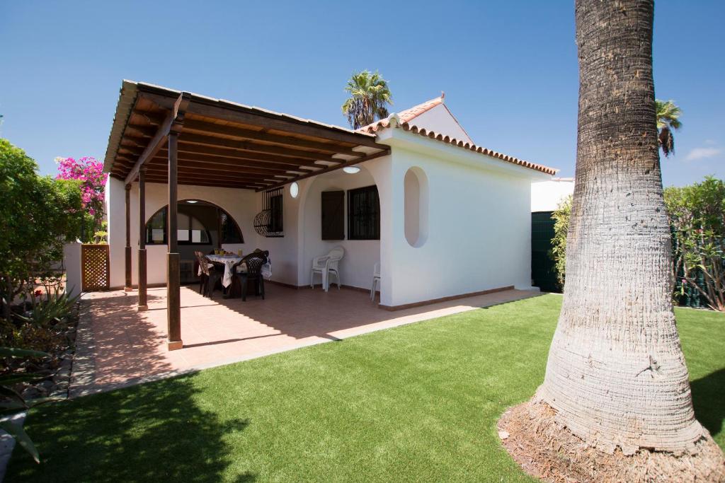a white house with a table and a palm tree at Serenity Garden in Maspalomas
