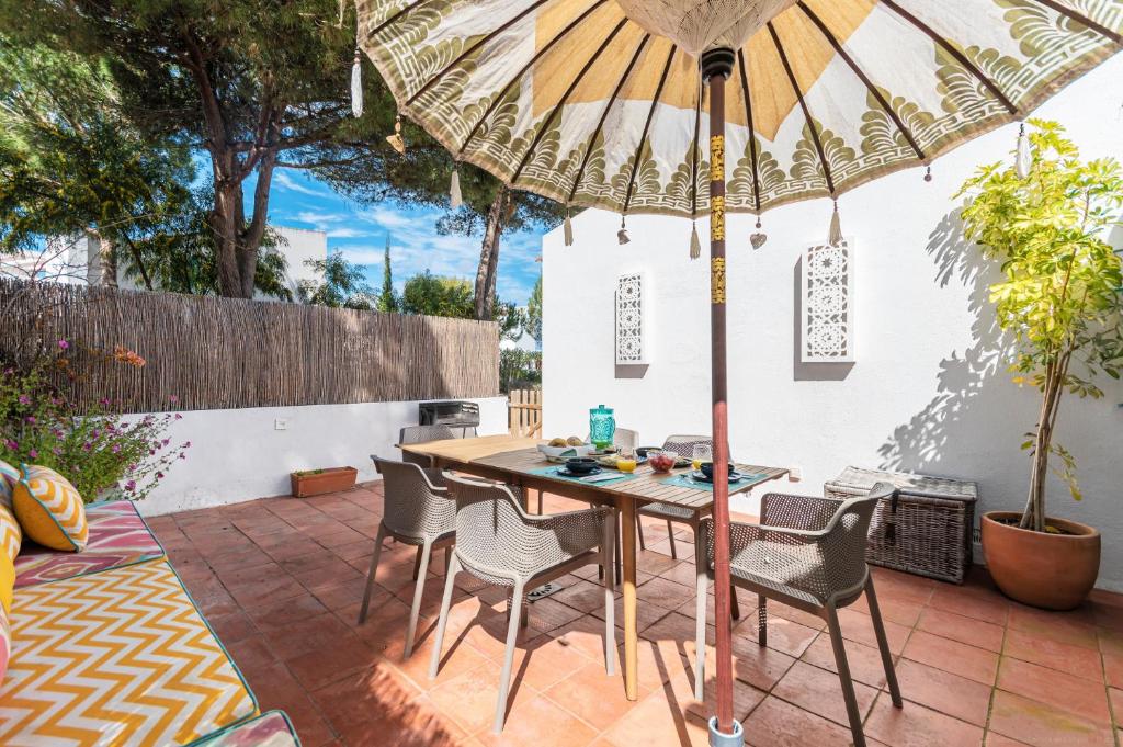 a wooden table and chairs under an umbrella on a patio at Casa Prainha, Alvor para 10 pessoas in Alvor