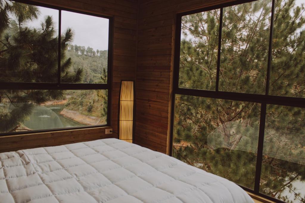 1 dormitorio con 1 cama grande y ventanas grandes en Cabañas Refugio Himalaya, en Guatapé