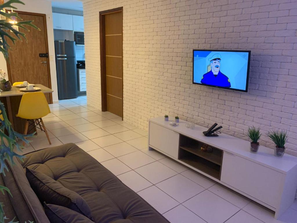 a living room with a tv on a brick wall at Apartamento em Maceió in Maceió