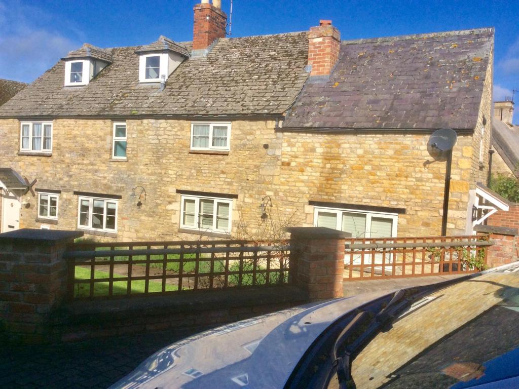 a house with a fence in front of it at Virginia Cottage in Bulwick