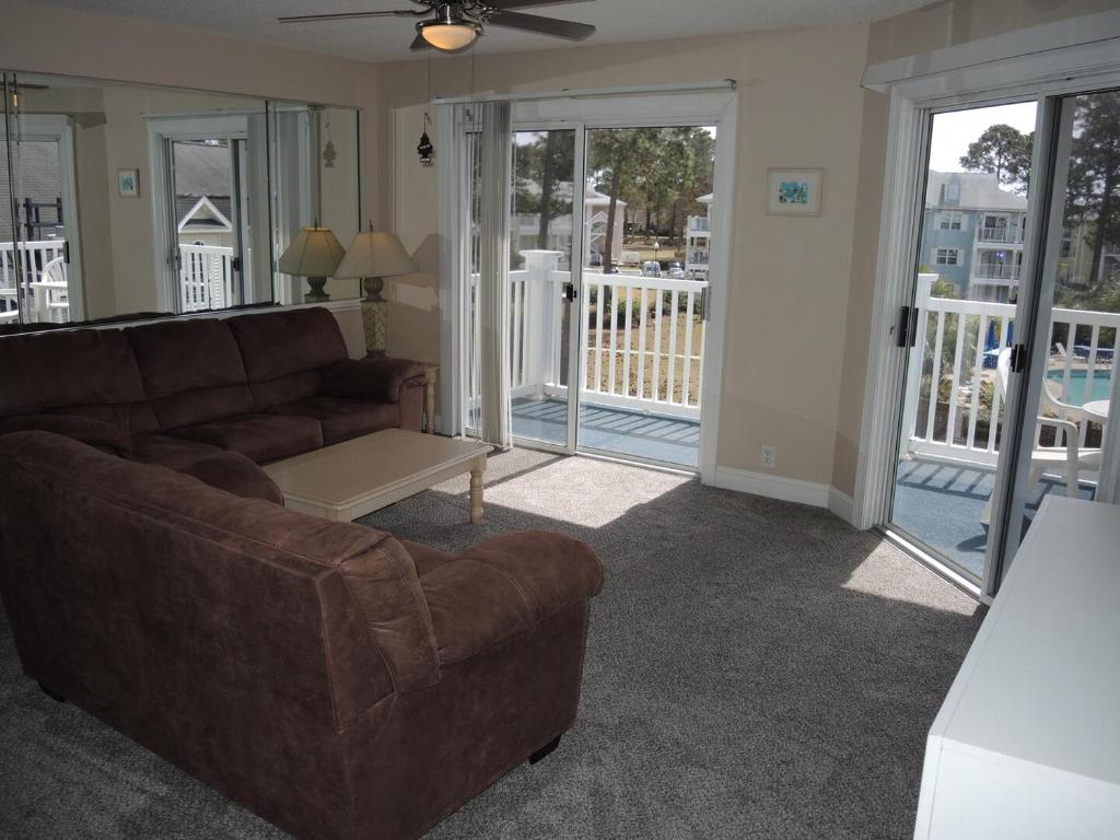 a living room with a brown couch and sliding glass doors at Brunswick Plantation Golf Resort 1509M in Calabash
