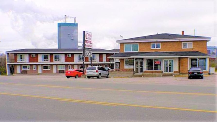 a building with cars parked in a parking lot at Chalet Inn Motel in Dryden