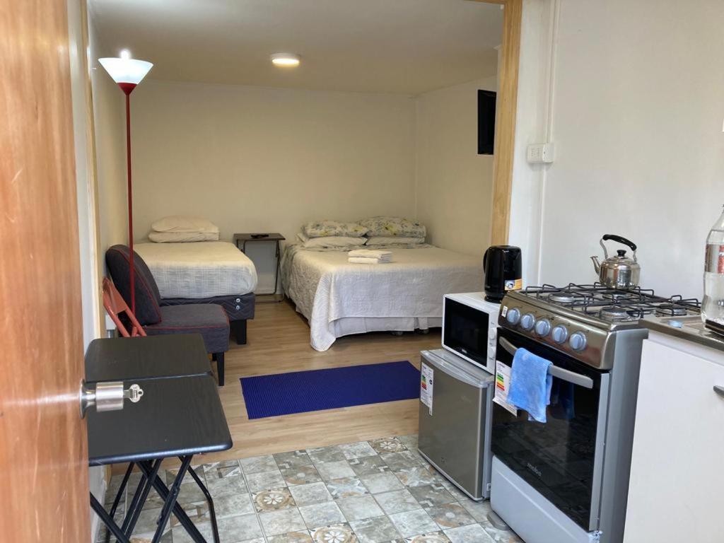 une cuisine avec une cuisinière et une chambre avec deux lits dans l'établissement Lepihue III, à Puerto Montt