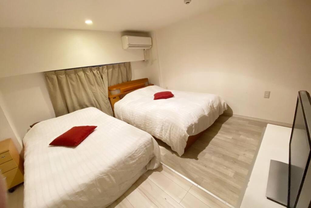 Habitación con 2 camas con almohadas rojas. en Takemura Building 107, en Tokio