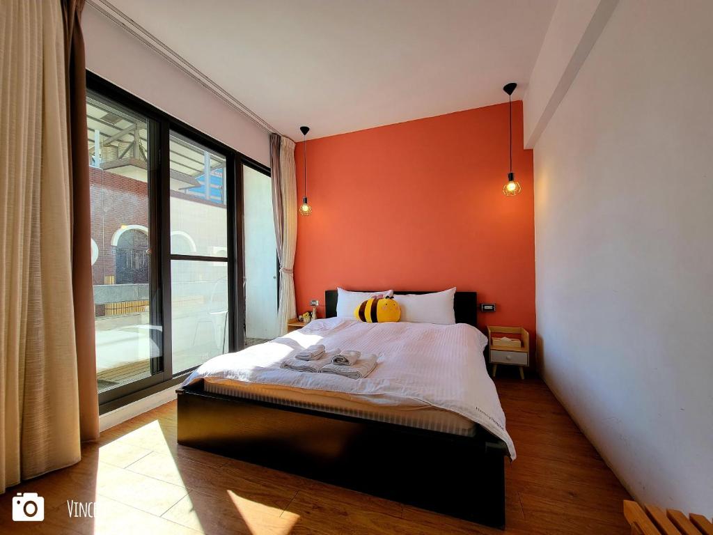 a bedroom with an orange wall and a bed at Honey House Tainan in Tainan