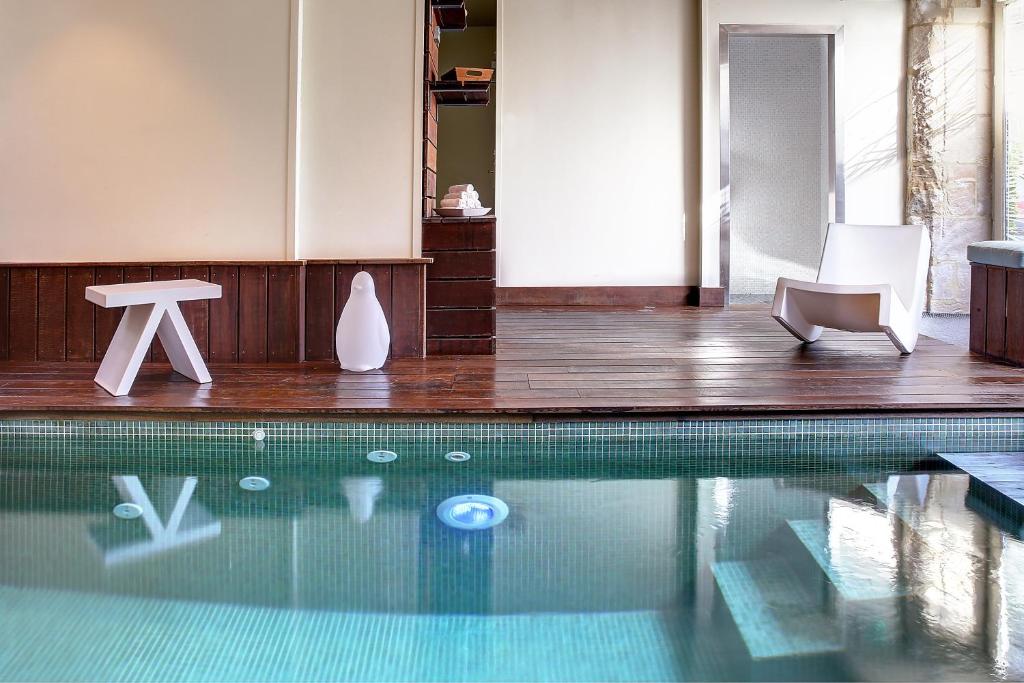 - une piscine avec 2 chaises blanches et une table dans l'établissement Hotel Restaurant Le Dauphin et Le Spa du Prieuré, à Caen
