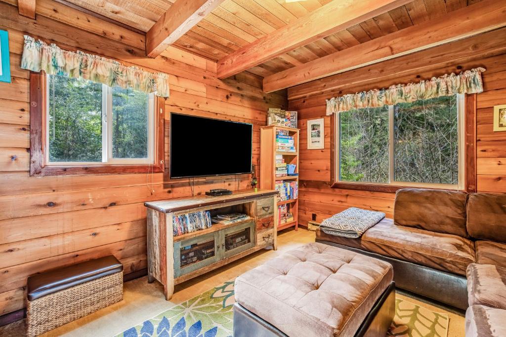 a living room with a television in a log cabin at The Beanstalk in Otis