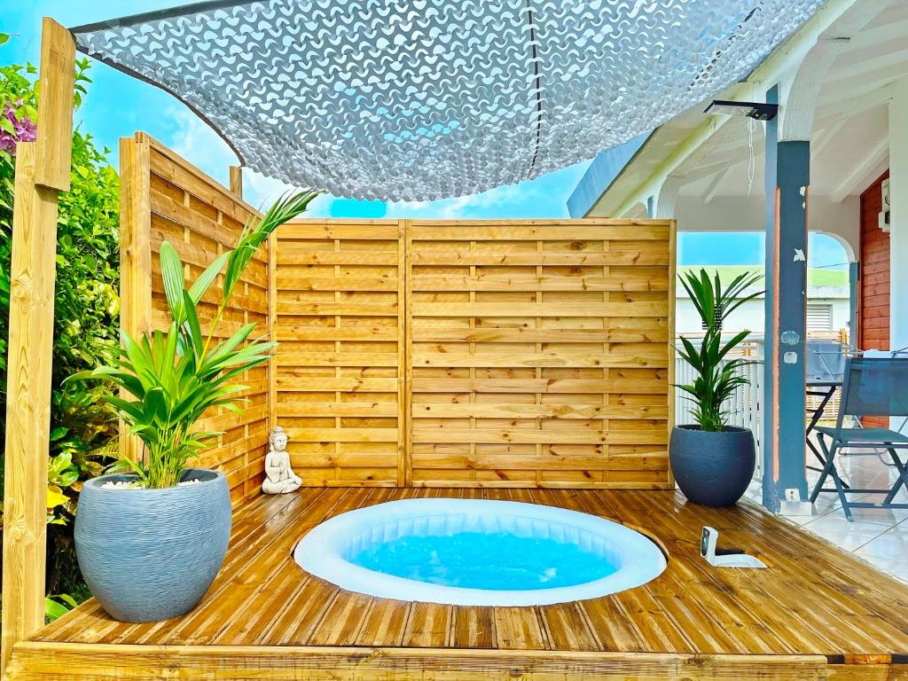 a hot tub on a deck with two potted plants at Sopraia Lodge in Les Abymes