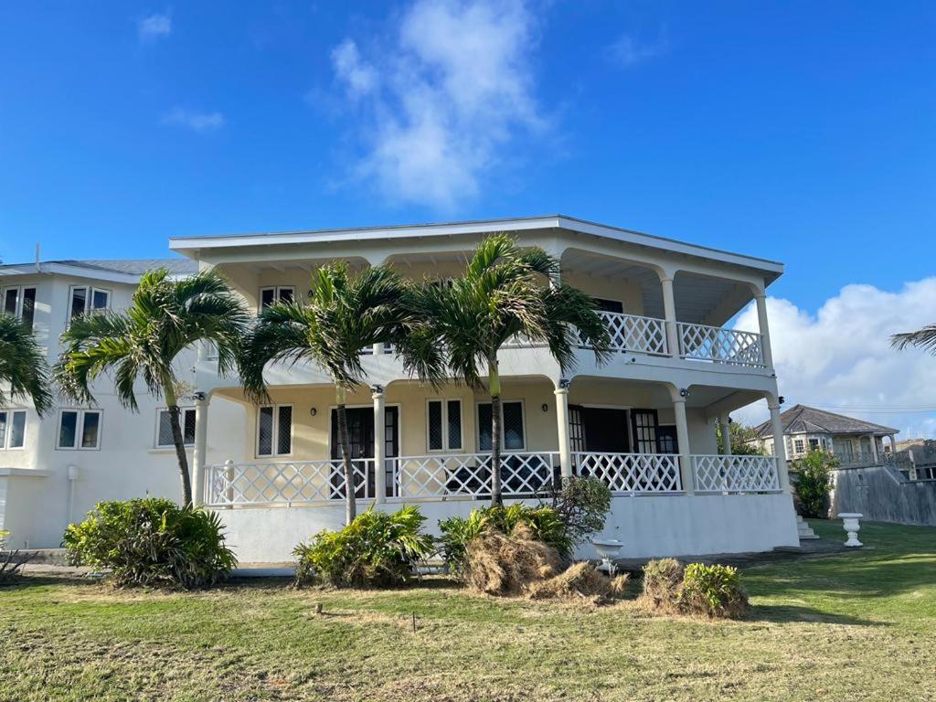 a white house with palm trees in front of it at 'PARLATUVIER' 4 bedroom ocean view home in Saint Philip