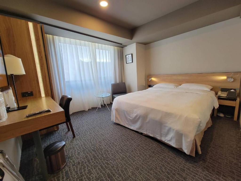 a hotel room with a large bed and a desk at Simple + Hotel in Taipei